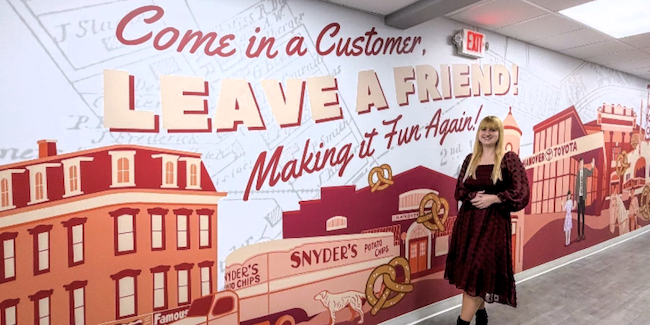 Moriah Tyler in front of a mural she painted